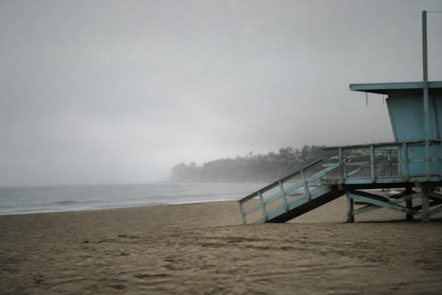 Low marine layer cloud sitting over a Southern California beach at mid morning, lifeguard tower in flat grey light